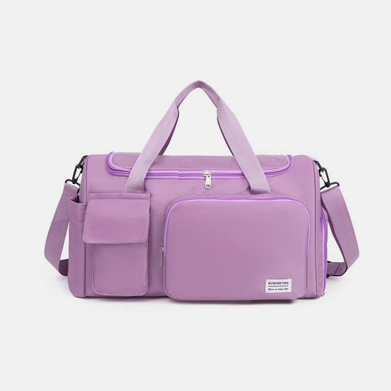 Lilac oversize oxford cloth travel bag with a structured silhouette, dual top handles, detachable shoulder strap, zippered compartments, and flap-front pockets.