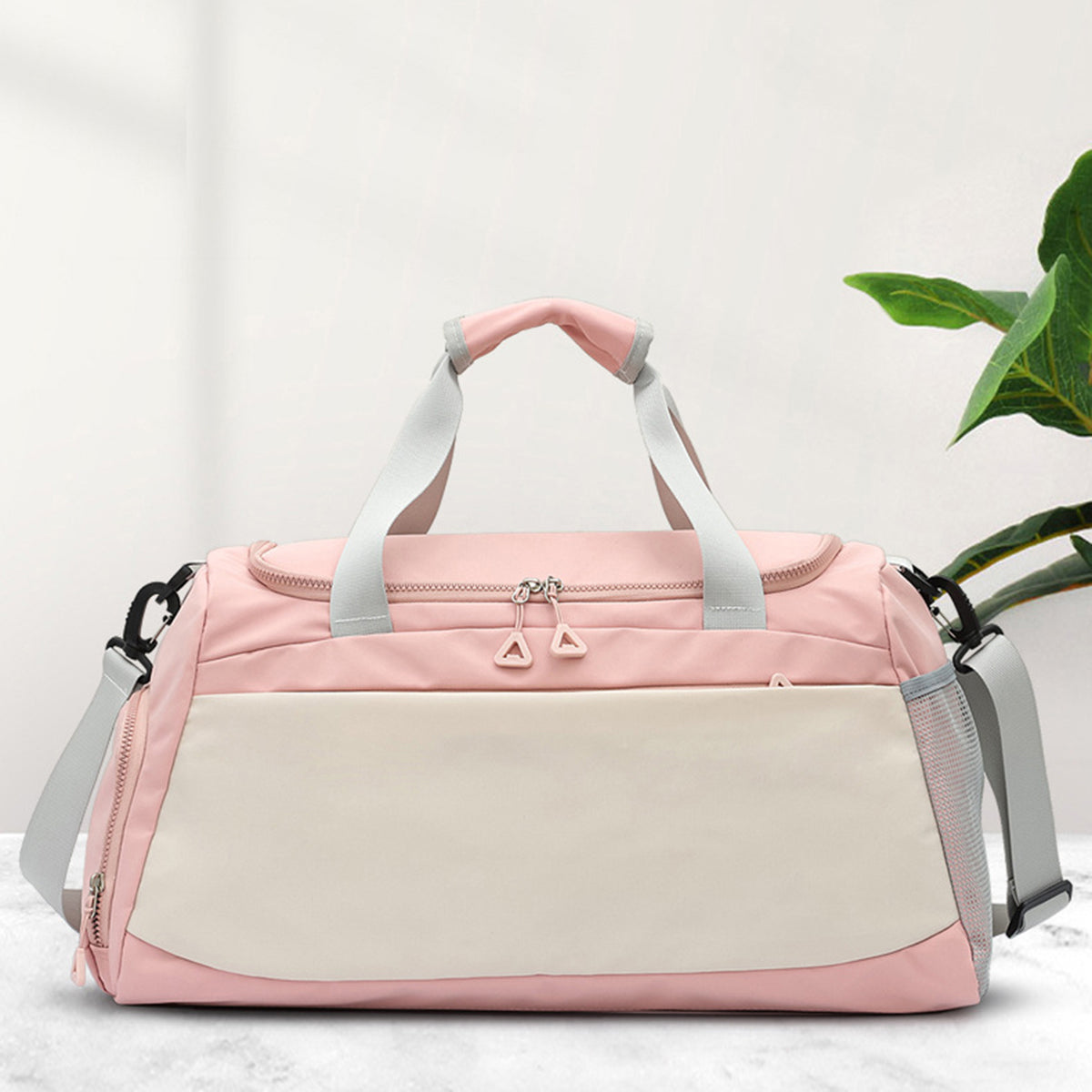Oversize pink and cream Oxford cloth travel bag with a roomy duffel silhouette, dual handles, adjustable shoulder strap, and multiple zippered pockets.