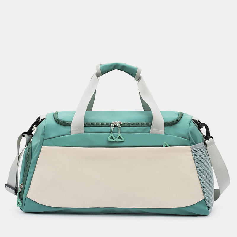 Oversize teal Oxford cloth travel bag in a softly structured duffel silhouette with dual top handles, adjustable shoulder strap, and multiple zippered pockets.