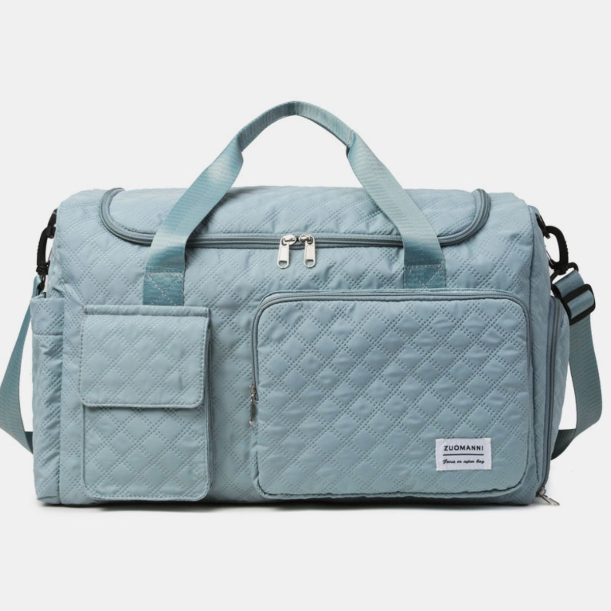 Oversize pale blue Oxford cloth travel bag with a quilted duffel silhouette, zip-top closure, sturdy handles, shoulder strap, and multiple exterior pockets.