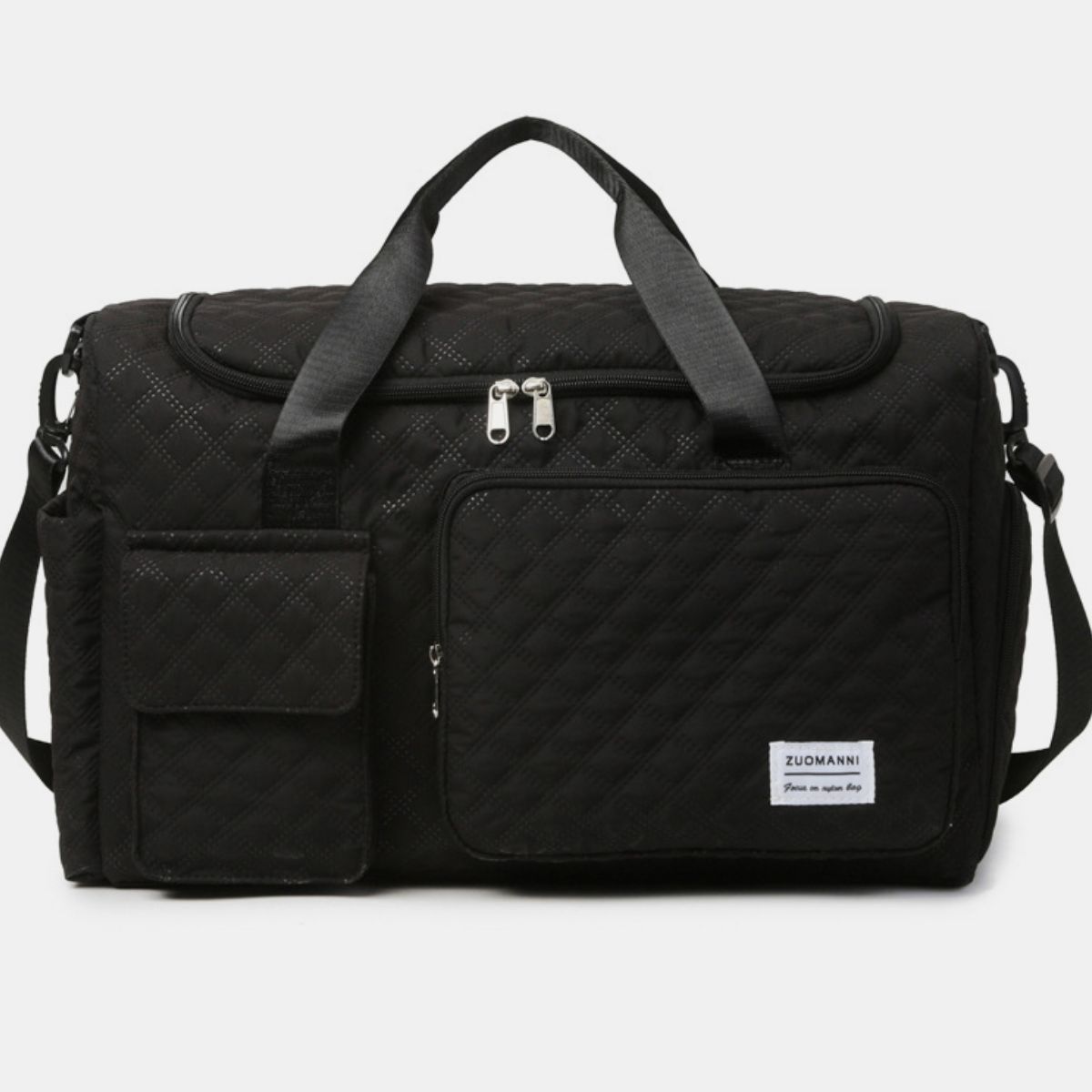 Oversize black Oxford cloth travel bag with a quilted duffel silhouette, multiple zip and flap pockets, sturdy top handles, and a detachable shoulder strap.
