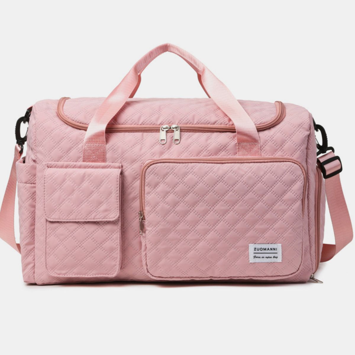 Oversize pink Oxford cloth travel bag with a quilted duffel silhouette, dual top handles, adjustable shoulder strap, zip-top closure, and multiple exterior pockets.