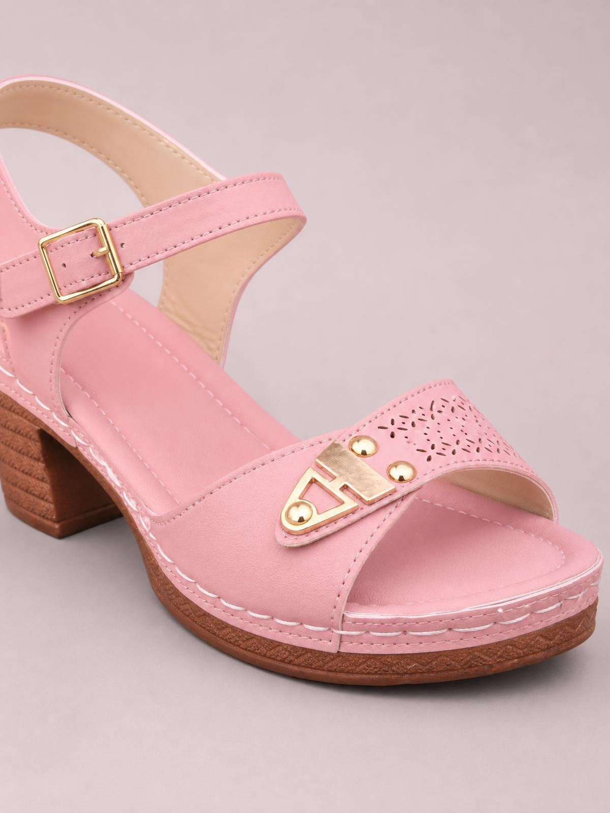 Pink peep toe sandals feature mid block heels, adjustable ankle buckles, perforated front straps, gold-tone embellishments, and visible stitched construction.