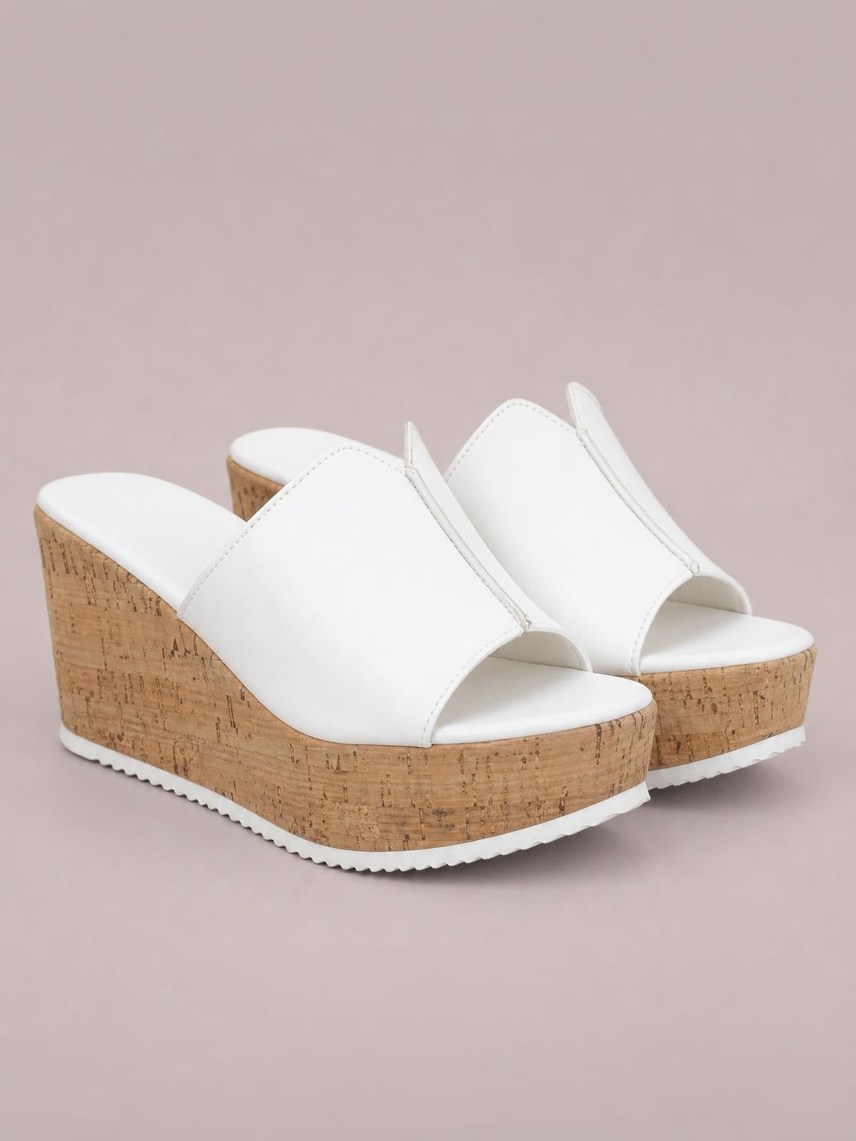 White peep-toe high heel sandals with smooth wide crossover uppers, open toes, and tall cork-textured wedge platform soles.