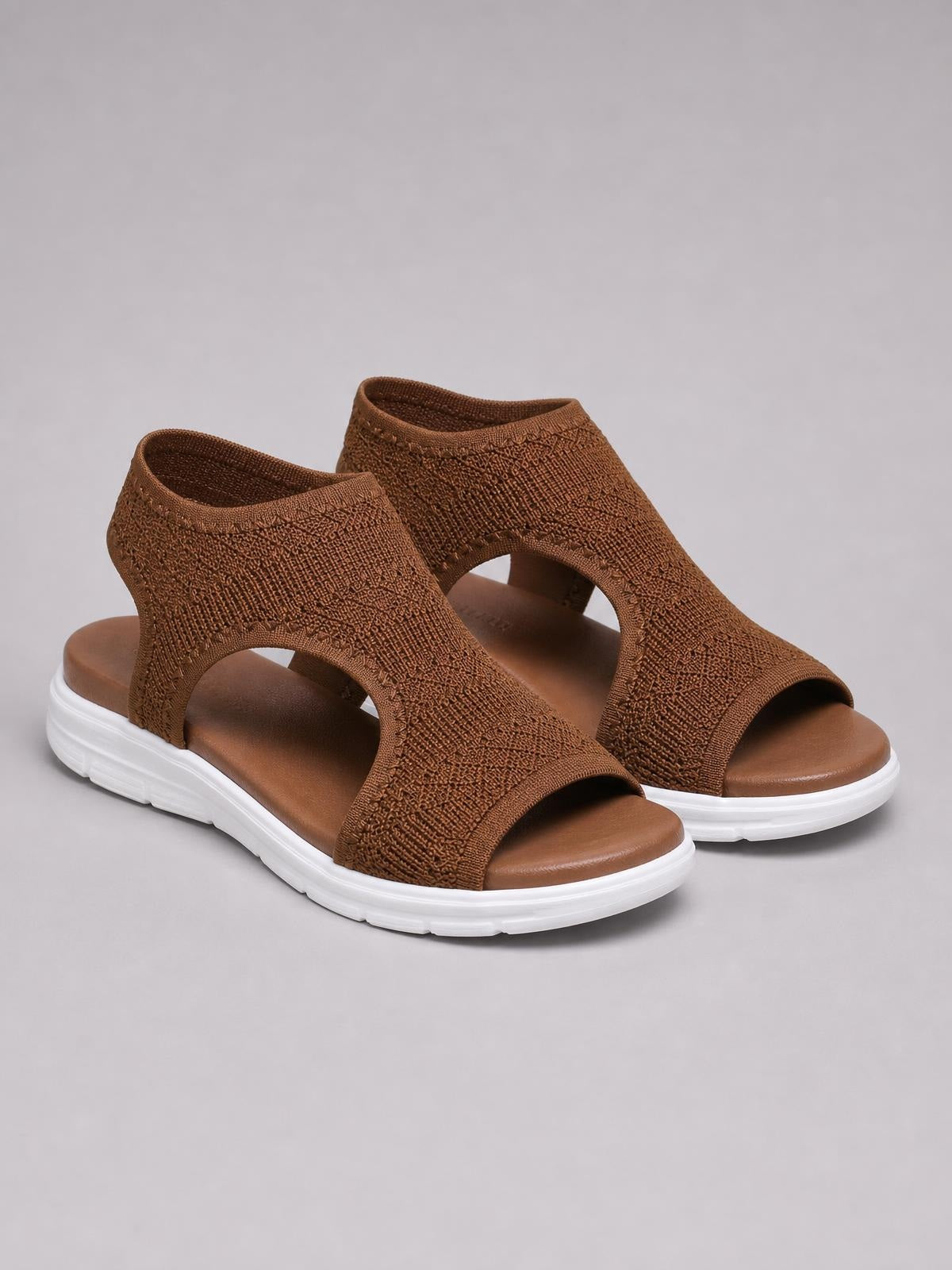 Brown solid-color peep-toe flat sandals with textured cloth uppers, open sides, and thick white rubber soles.