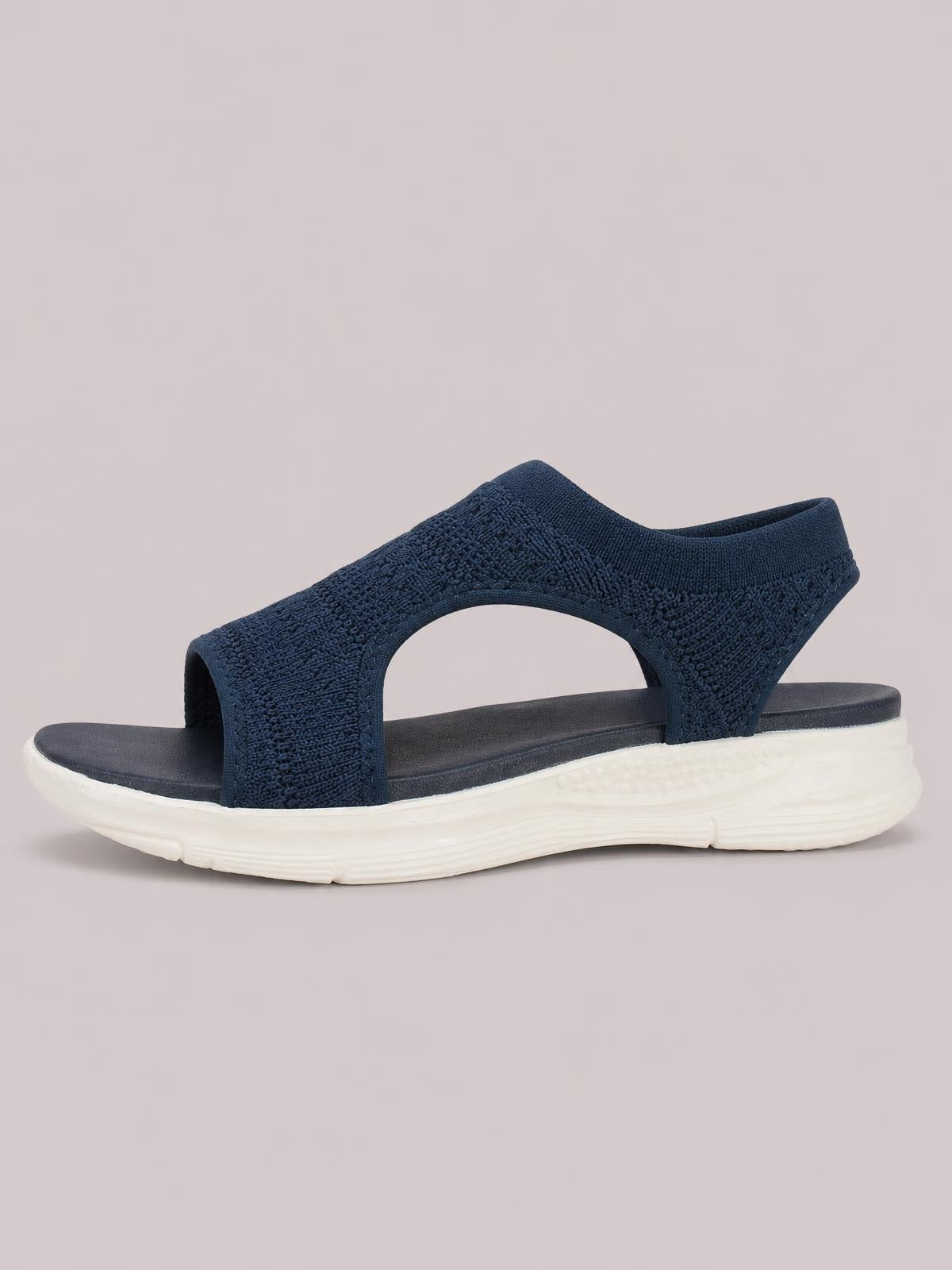 Solid navy peep toe sandals feature textured cloth straps, an open-sided silhouette, cushioned footbed, and a thick white rubber flat sole.