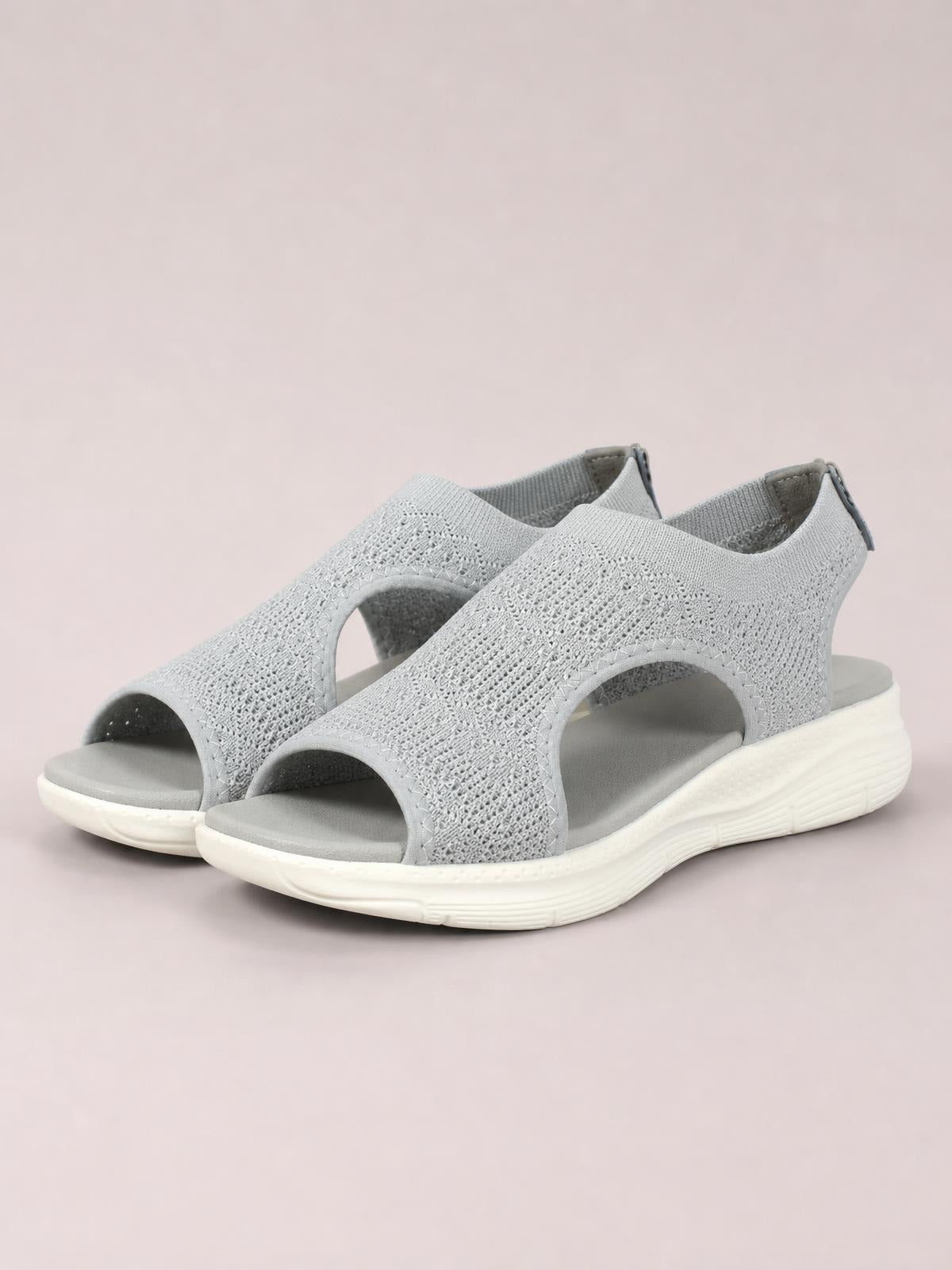 Light gray solid-color peep-toe sandals feature textured cloth uppers, wide side cutouts, open toes, and flat rubber soles with a subtle tread.