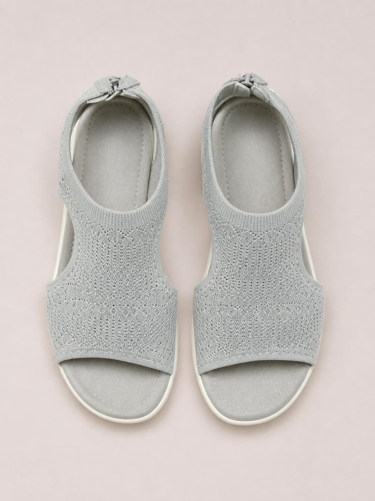 Pair of light gray peep toe solid color sandals with textured cloth uppers, open sides, cushioned footbeds, and flat rubber soles.