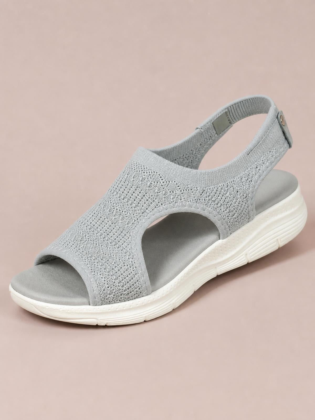 Solid gray peep toe sandals with a textured cloth upper, adjustable ankle strap, open sides, cushioned footbed, and flat white rubber sole.