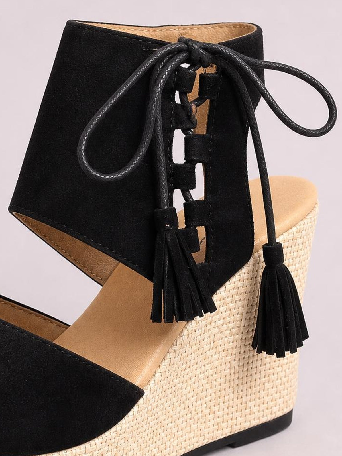 Black suede peep toe wedge sandals feature lace-up ankle straps with tassel ties, tan insoles, and textured woven mid-height wedge soles.
