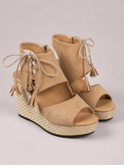 Tan suede peep toe wedge sandals with lace-up ankle ties, tassel details, woven platform midsoles, and comfortable mid-height wedges.