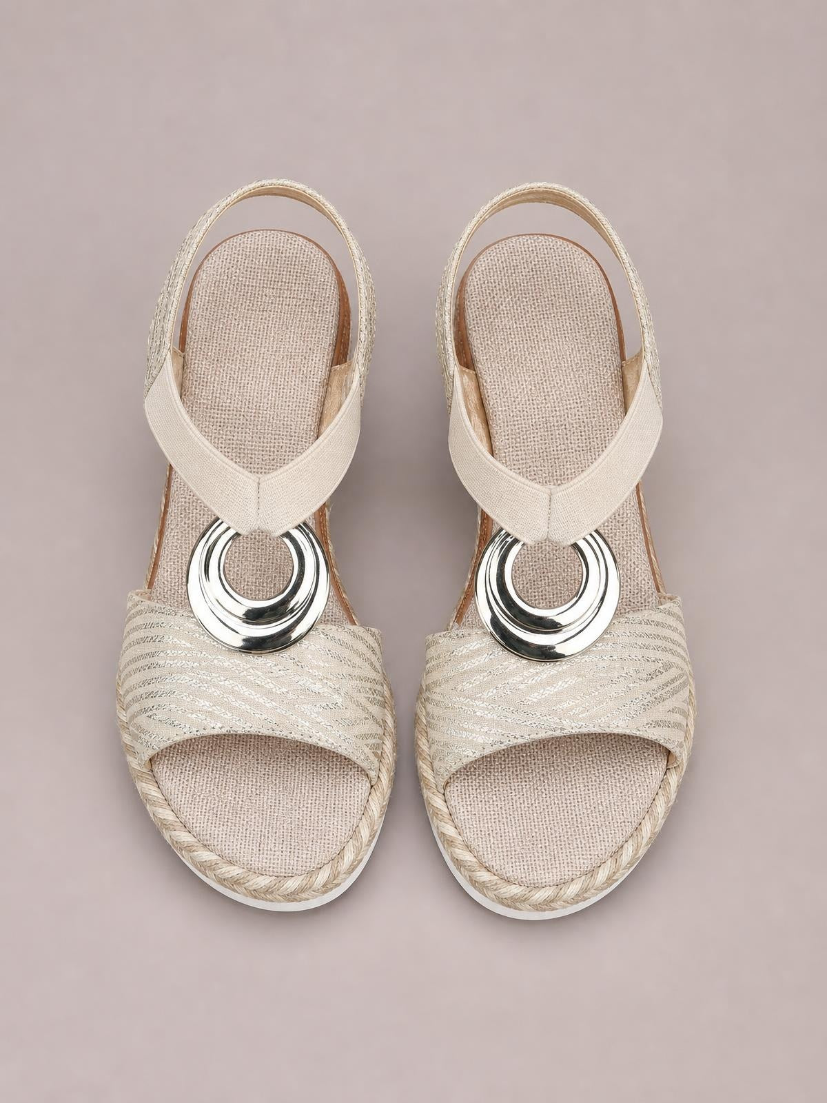 Beige peep toe wedge sandals feature crisscross straps, textured woven uppers, braided trim, and polished silver ring embellishments.