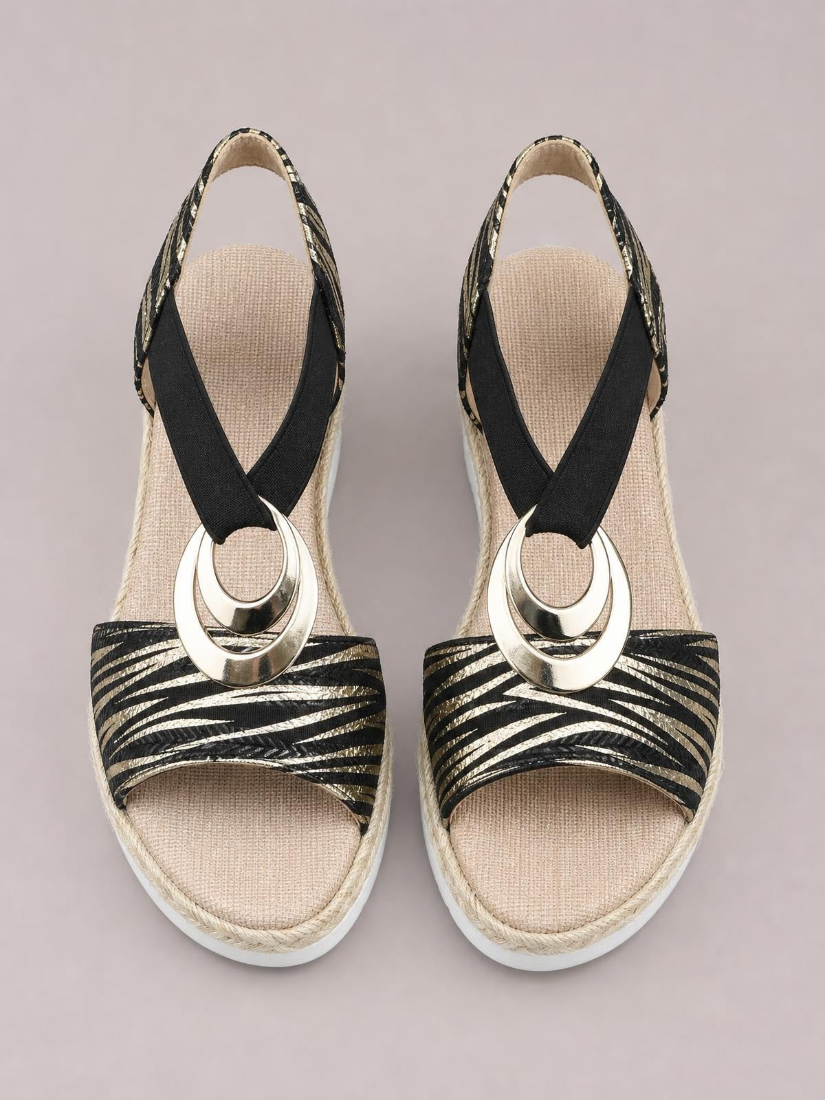 Black and metallic striped peep toe wedge sandals feature crisscross straps, gold-tone circular hardware, woven insoles, and braided wedge trim.