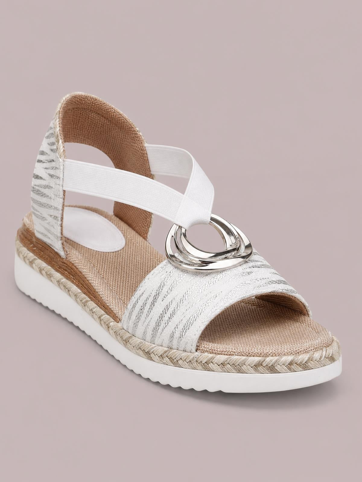 White peep toe wedge sandals feature woven espadrille trim, silver ring embellishment, ankle straps, and a textured rubber platform sole.