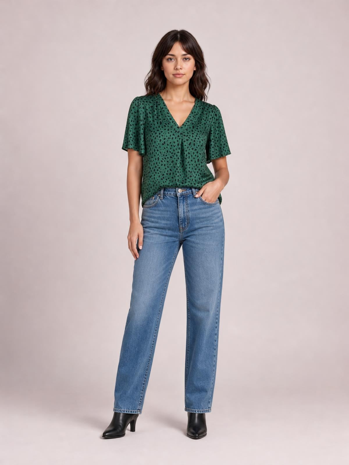 A model wears a green leopard-print V-neck blouse with short flutter sleeves, a relaxed regular-length silhouette, and a loose drape over jeans.