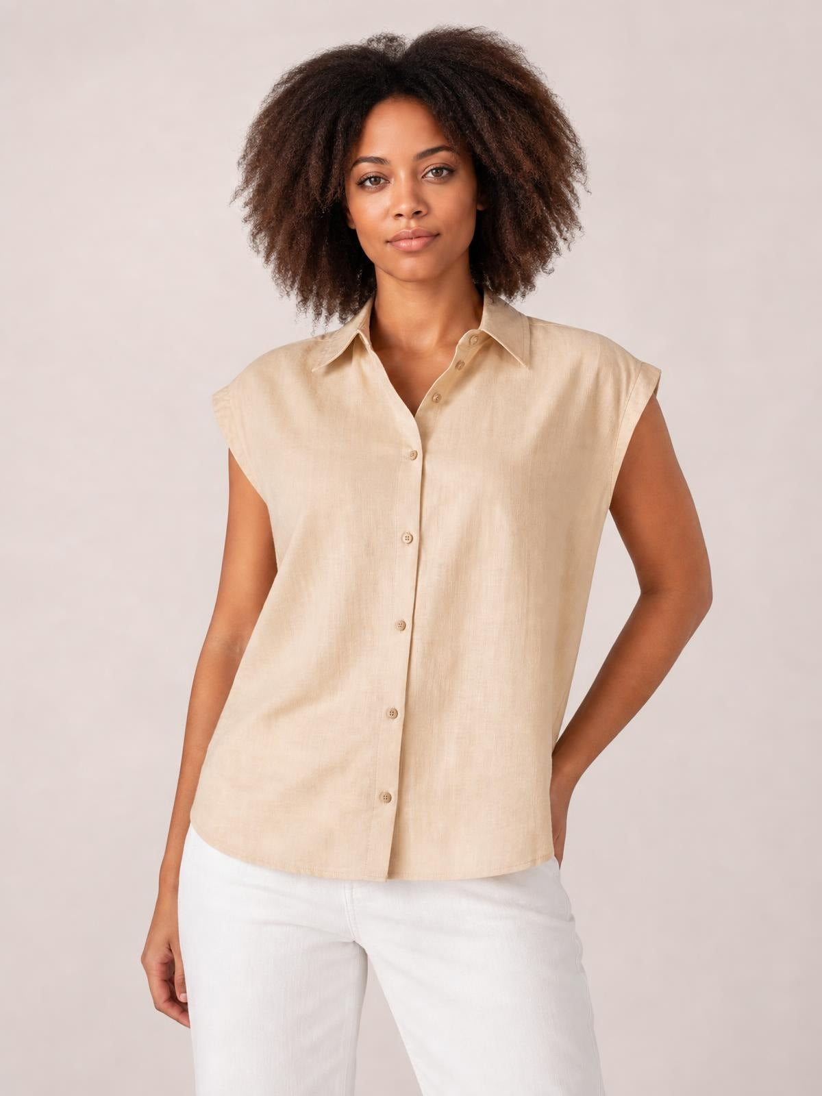 A model poses in a beige button-up shirt with a pointed collar, cap sleeves, front buttons, and a relaxed straight silhouette.