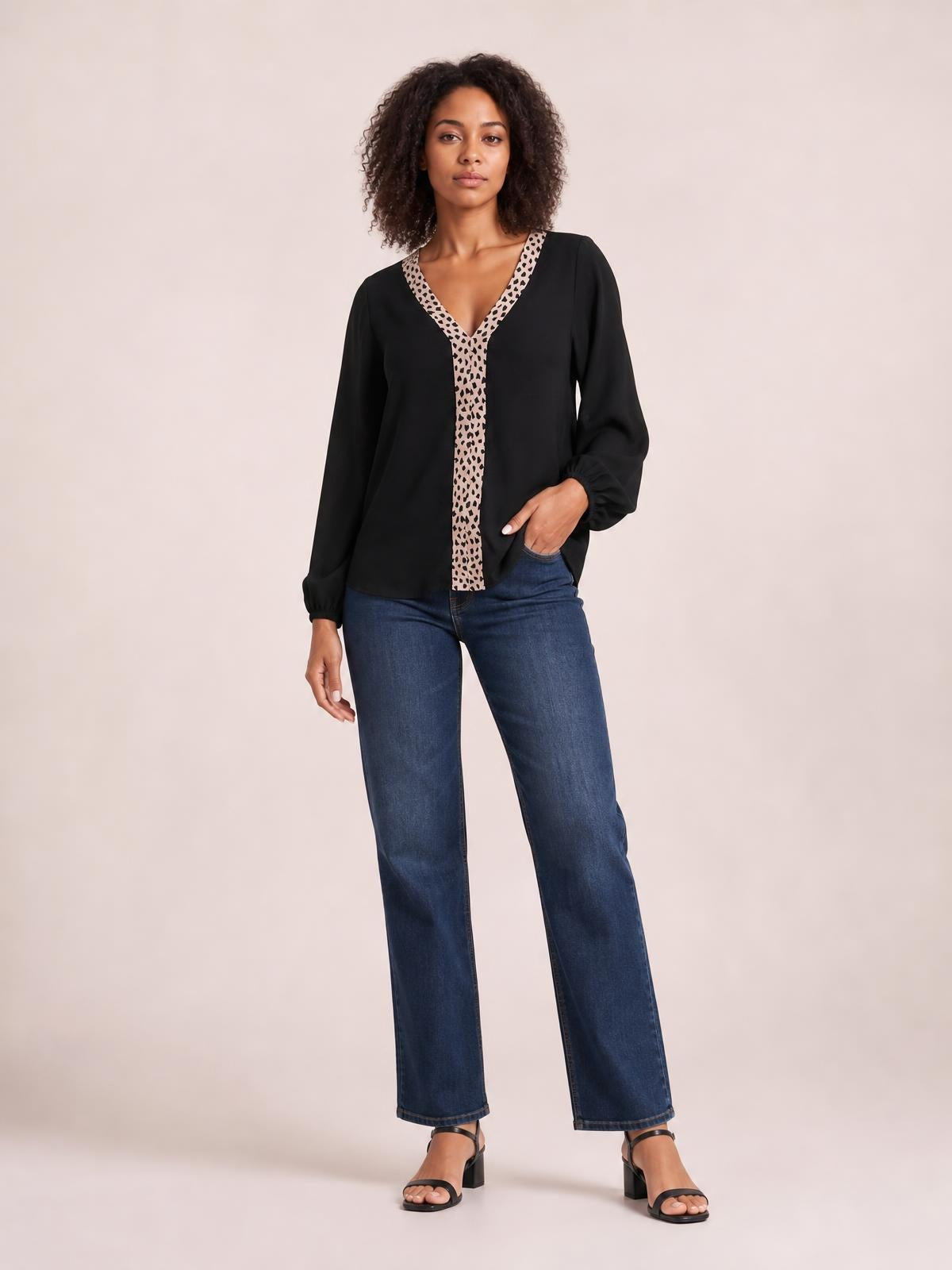 Model poses in a black long-sleeve blouse with a contrast leopard-print V-neck trim and front panel, relaxed silhouette, and gathered cuffs.