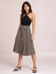 Model posing in a black crisscross halter neck dress with a solid fitted bodice, mocha printed gently flared skirt, and below-the-knee hem.