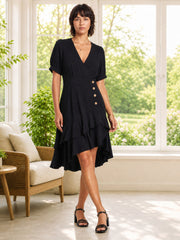 A model steps forward in a black surplice V-neck dress with short sleeves, defined waist, decorative front buttons, an A-line silhouette, and layered ruffle hem.