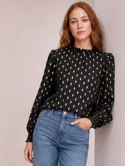Model poses in a black geometric print blouse with a frill neck, smocked detail, regular fit, and long puff lantern sleeves, paired with jeans.