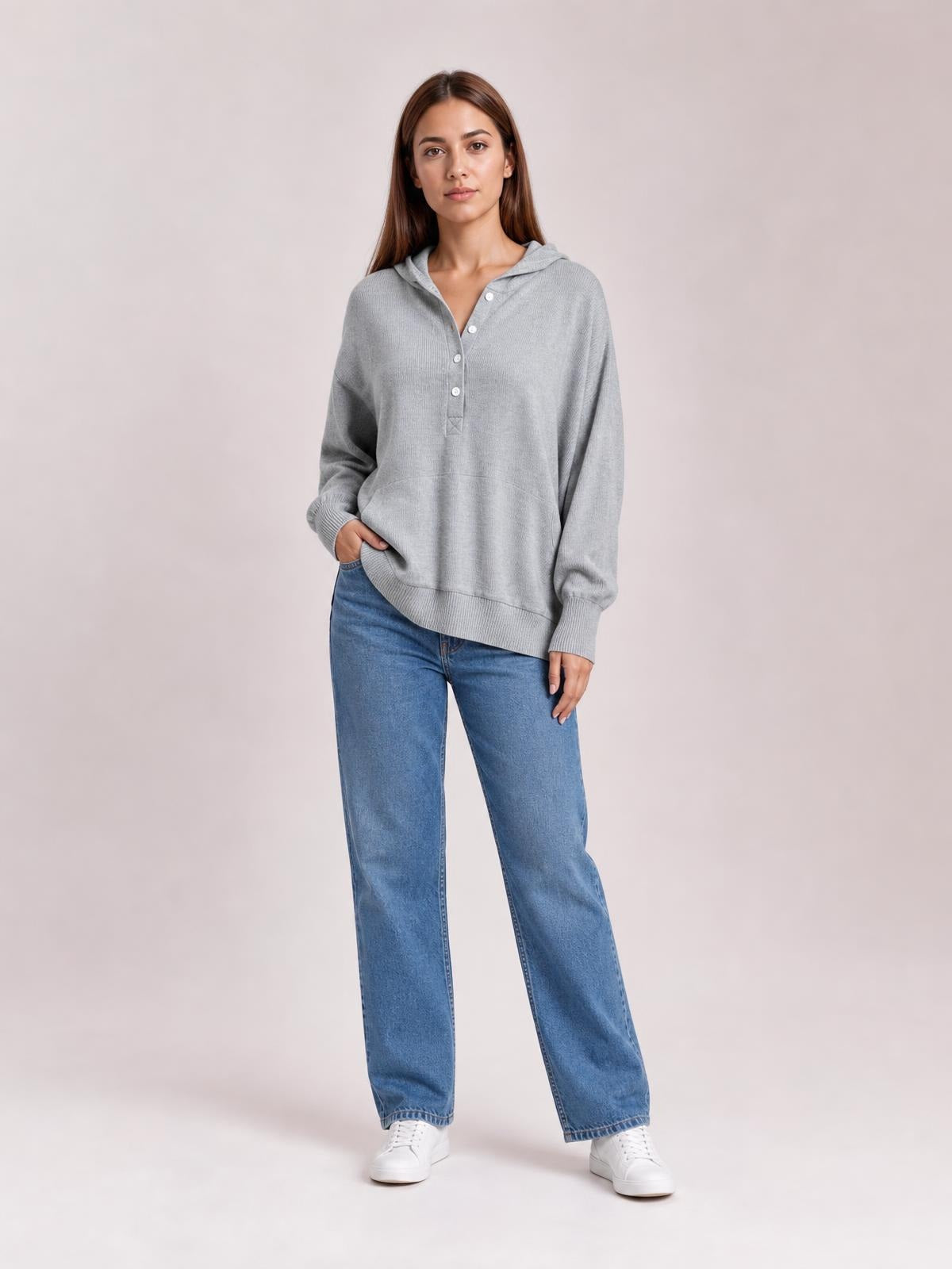 A model wears a light gray half-snap long sleeve hoodie with a relaxed silhouette, hood, button placket, ribbed cuffs and hem, and practical pockets.