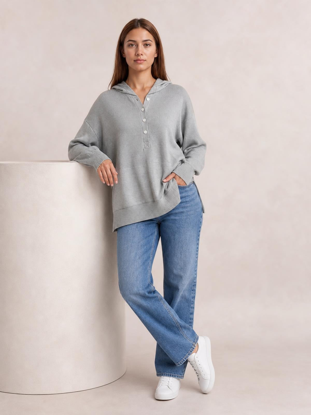 A model wears a loose gray half-snap long-sleeve hoodie with a drawstring hood, button placket, ribbed cuffs and hem, and side pockets.
