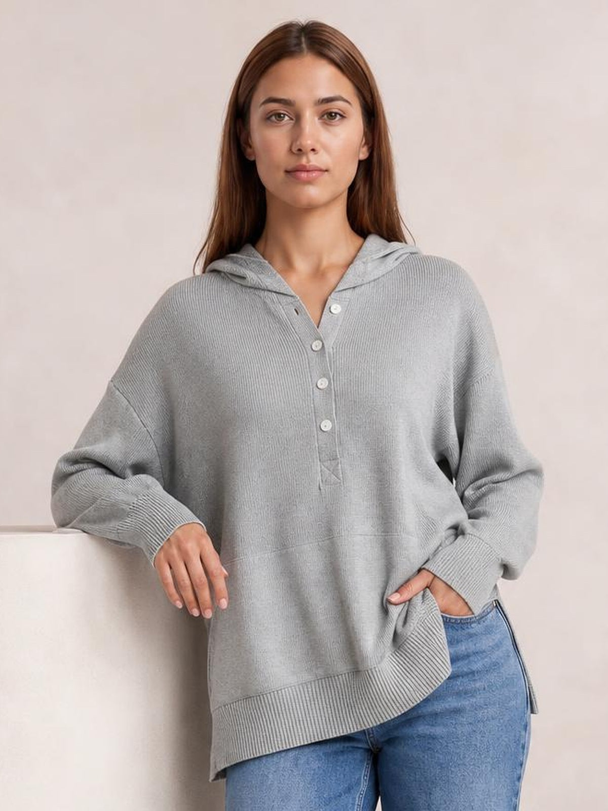 A model wears a light gray half-snap long sleeve hoodie with a button placket, hood, ribbed cuffs and hem, relaxed oversized silhouette, and side pockets.