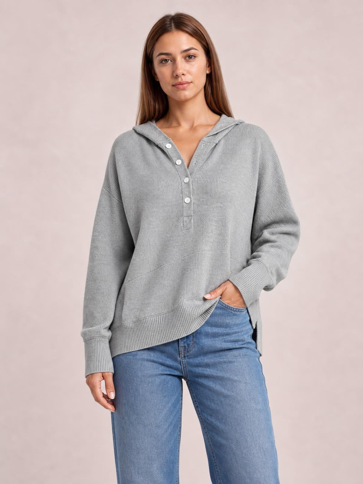 A model stands in a relaxed gray half-snap long sleeve hoodie with a hood, button placket, ribbed cuffs and hem, and a front pocket.