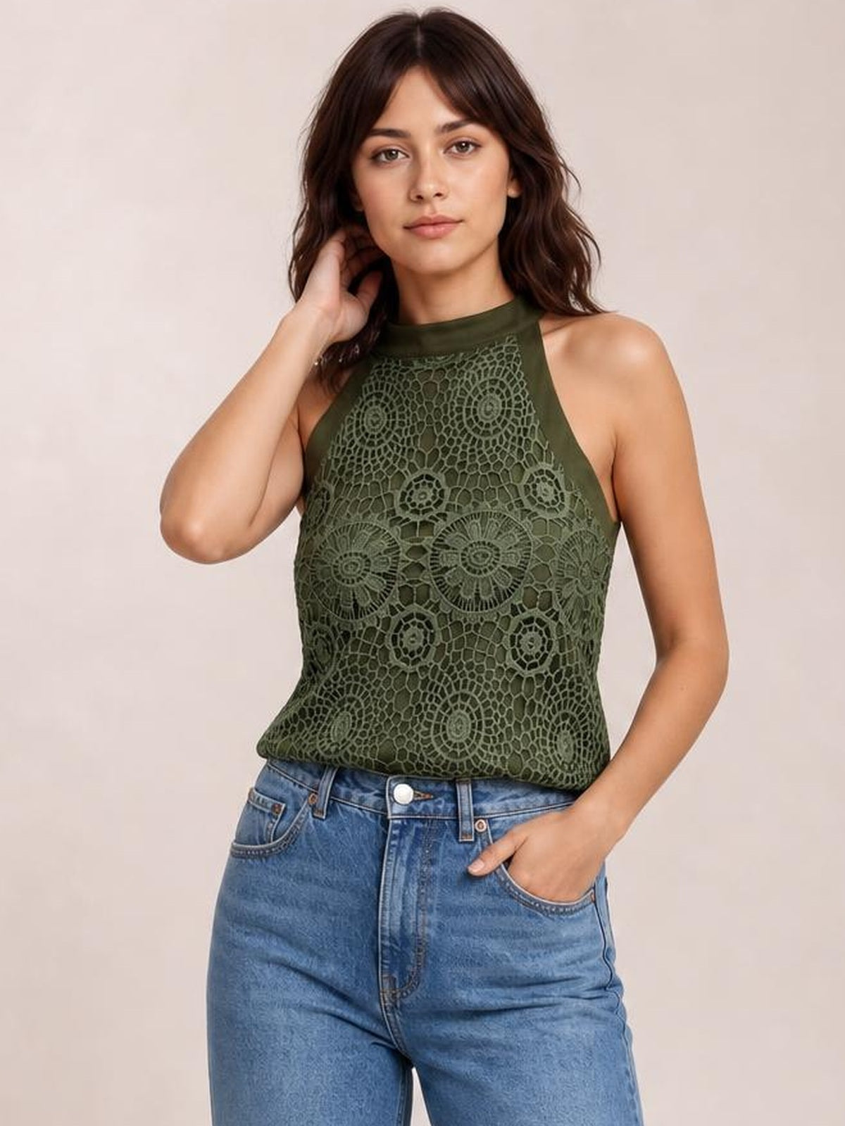 Model poses in a dark olive lace tank with a mock neck, sleeveless cut, opaque lining, fitted silhouette, and straight hem.