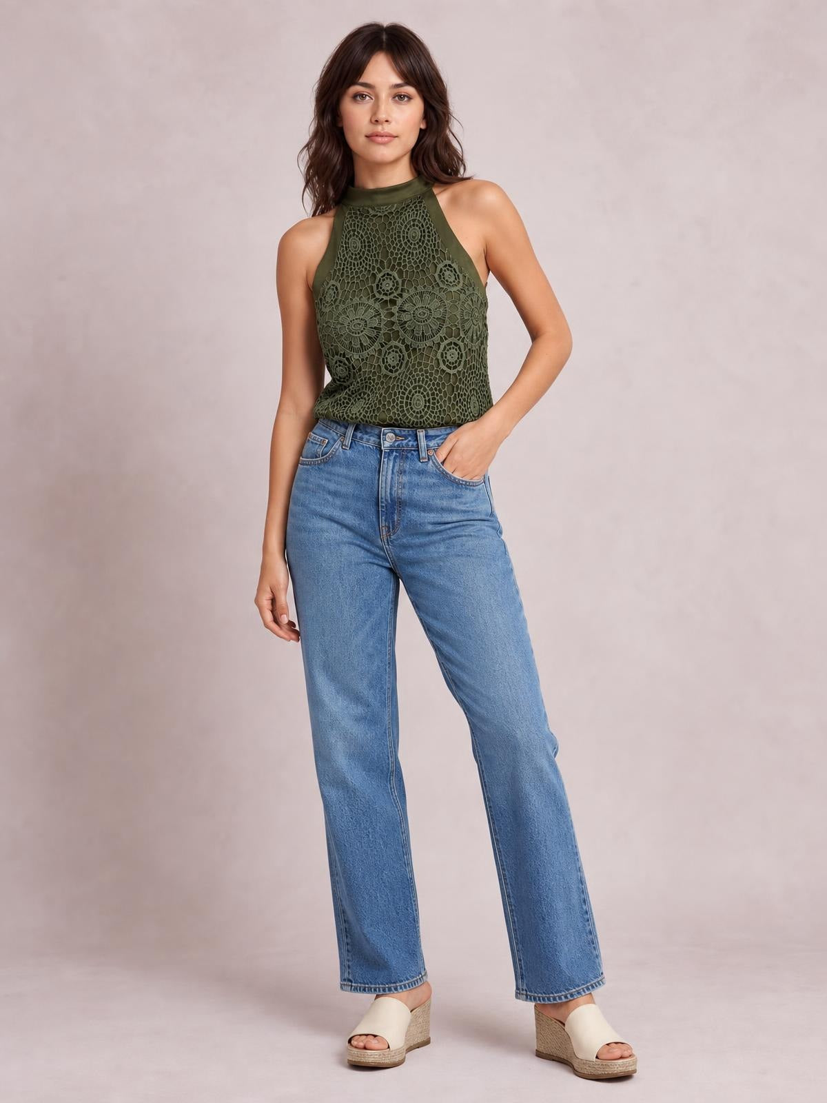 Model wearing an olive green lace mock-neck tank with a sleeveless cut, fitted silhouette, opaque construction, and floral lace detailing.