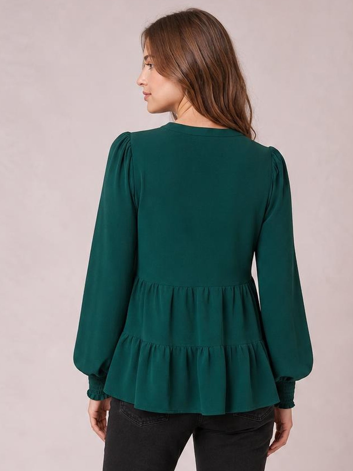 A model faces away wearing a deep teal lantern sleeve blouse with gathered tiers, a peplum silhouette, and ruched cuffs.