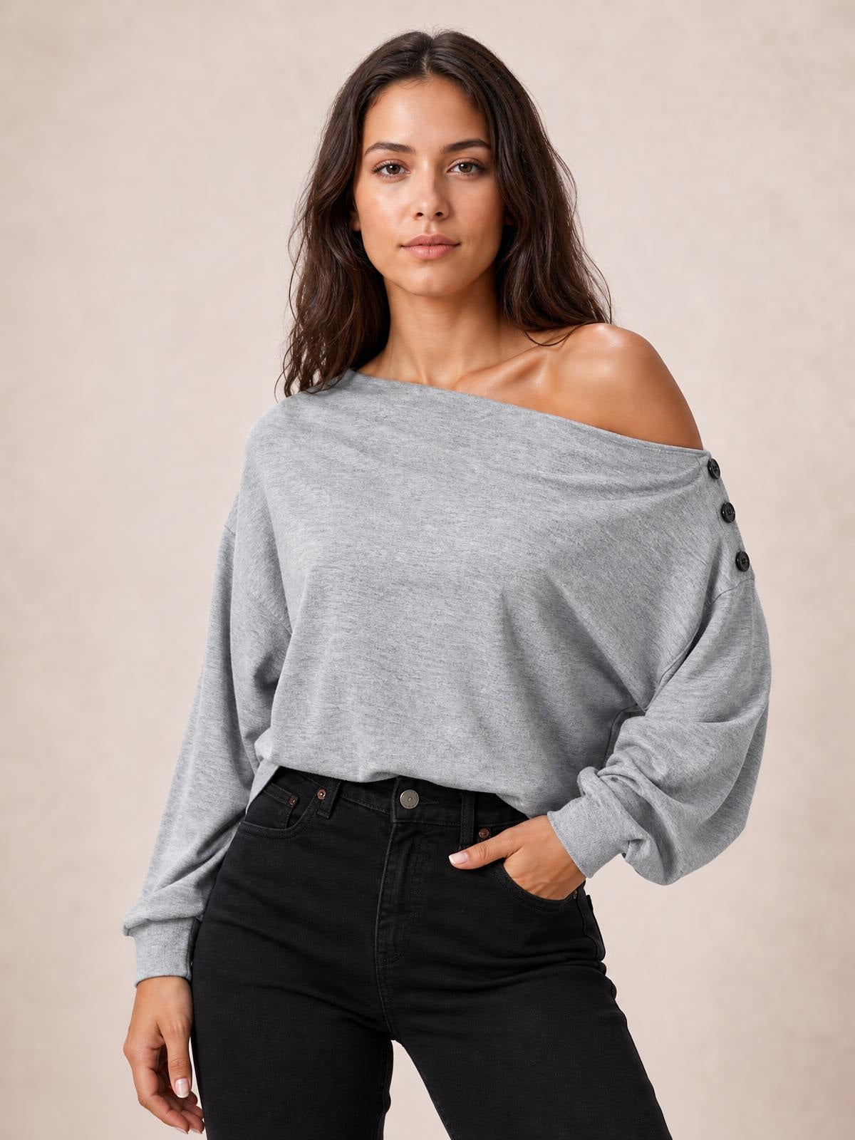 Model wears a solid gray off-shoulder long sleeve blouse with a relaxed silhouette, regular length, and button detailing along the shoulder.