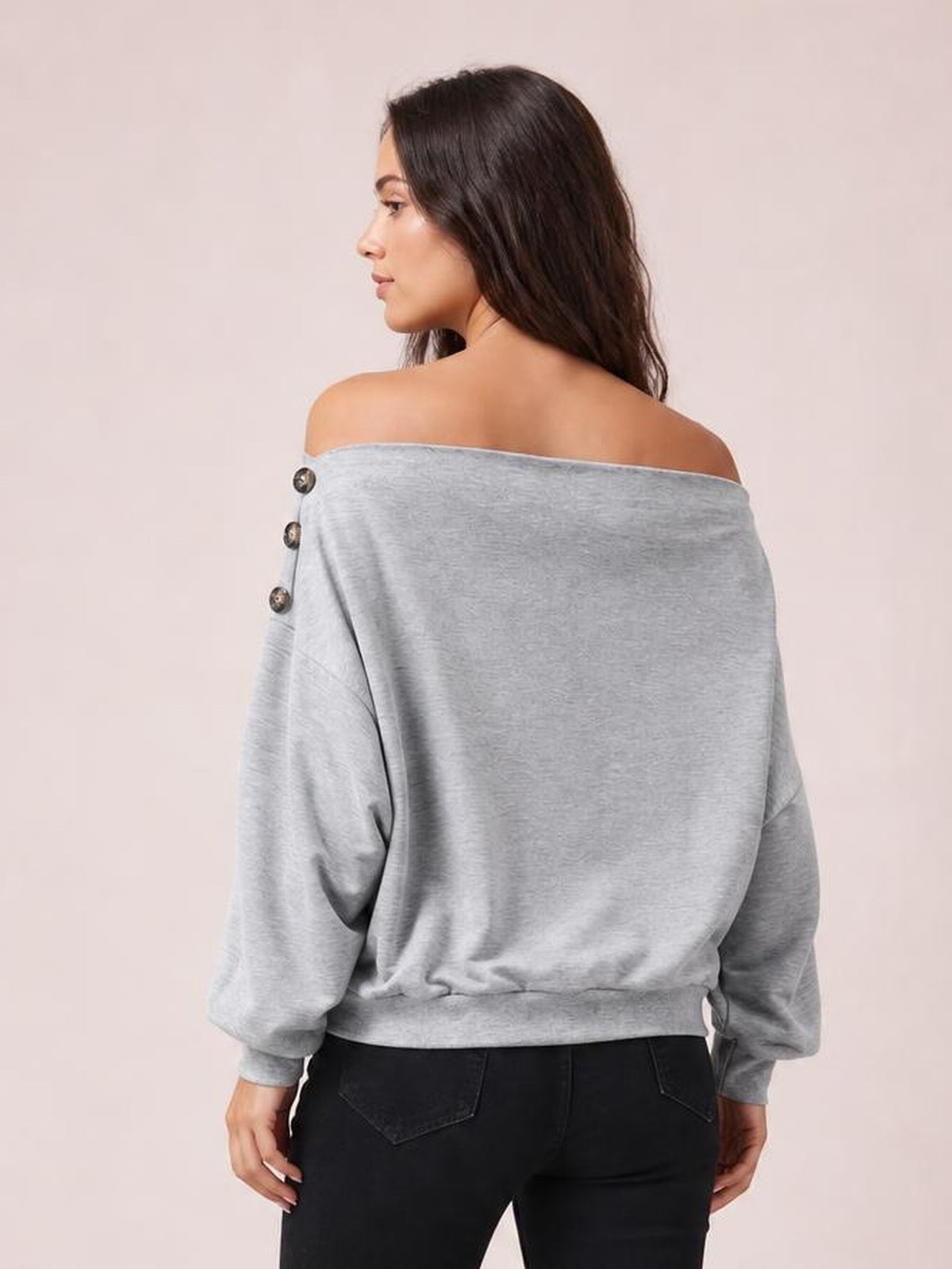 Model shown from behind in a light gray off-shoulder blouse with long sleeves, relaxed silhouette, regular length, and decorative buttons along the sleeve.