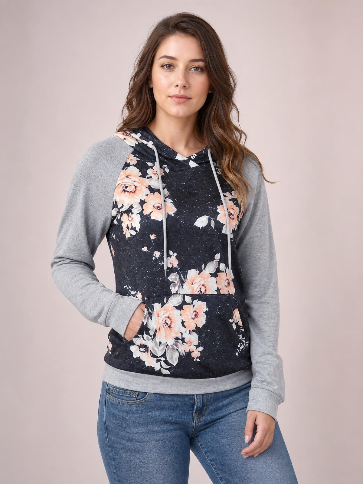 Model wears a casual floral printed hoodie with a black body, gray raglan long sleeves, drawstring hood, regular silhouette, and kangaroo pocket.
