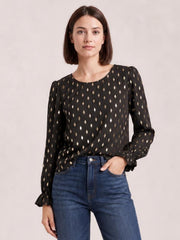 Model poses front-facing in a black printed blouse with a round neck, long puff sleeves, flounce cuffs, and a relaxed silhouette.