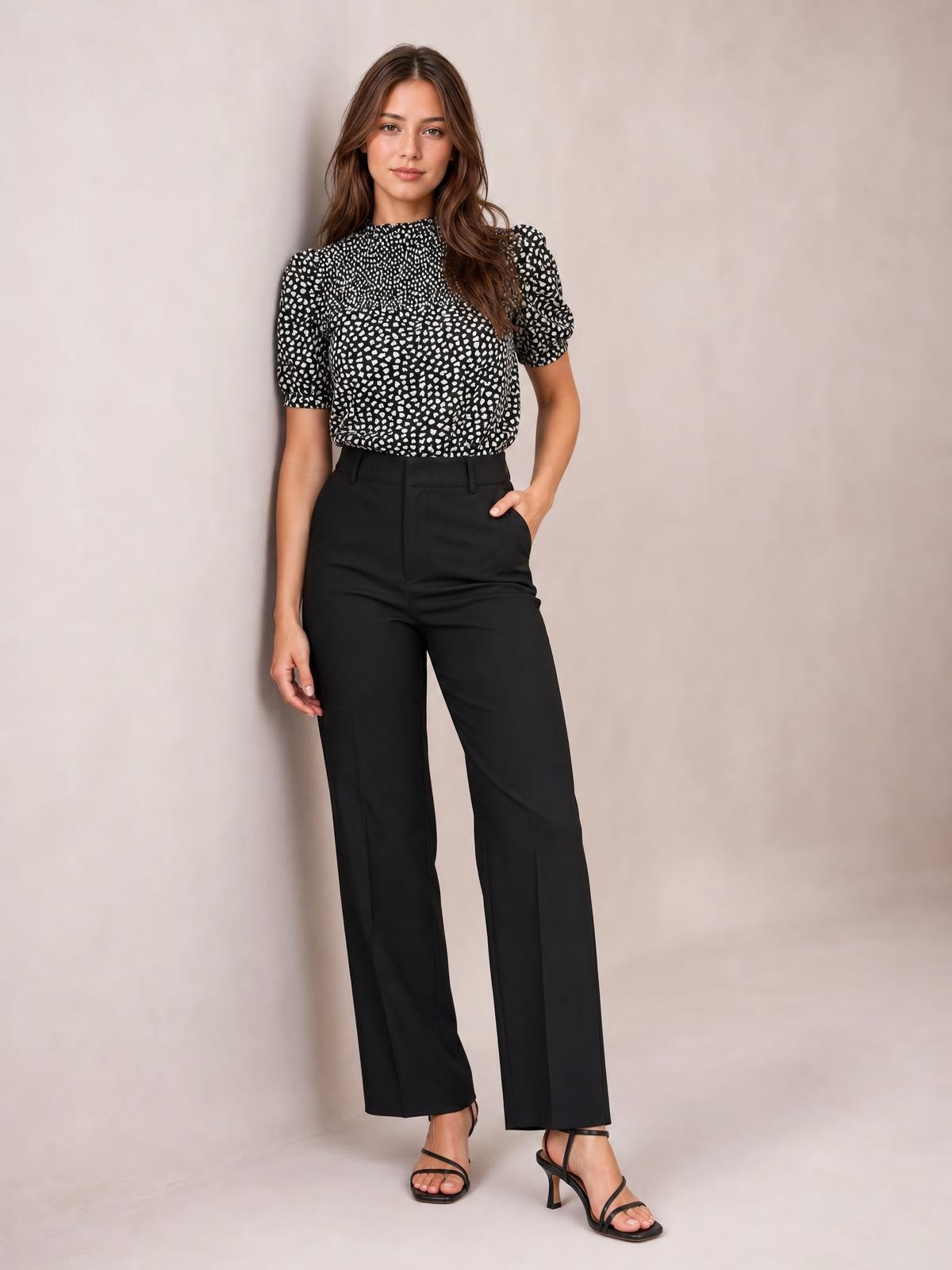 Model poses in a black-and-white printed round neck blouse with short puff sleeves and a relaxed long silhouette, styled with black wide-leg trousers.