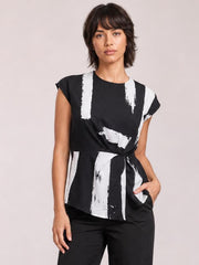 Model wears a black printed round-neck blouse with short regular sleeves, an opaque relaxed silhouette, and bold white abstract brushstroke pattern.