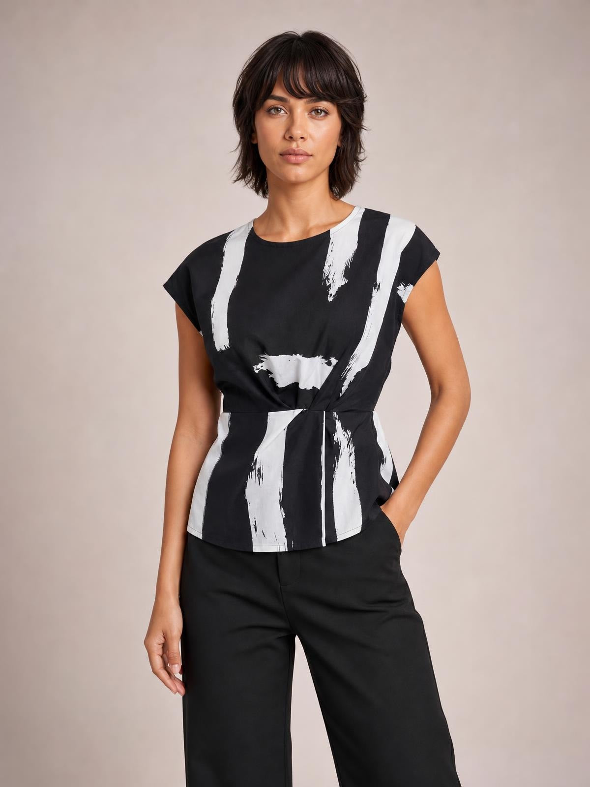 A model stands in a black and white printed blouse with a round neck, short regular sleeves, a cinched waist, and a gently flared long silhouette.