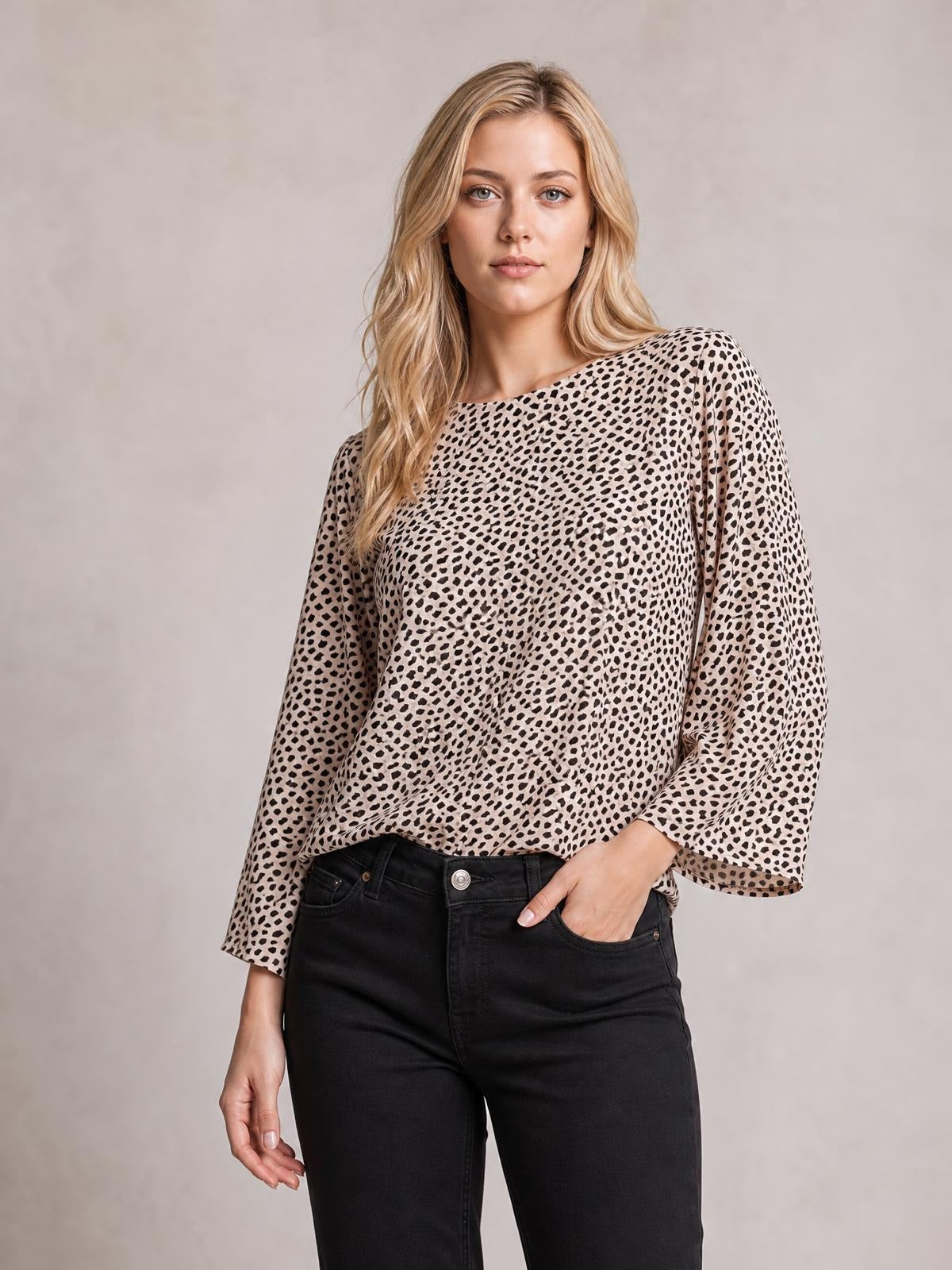 A model poses in a beige-and-black printed blouse with a broad neckline, loose regular silhouette, and three-quarter sleeves styled with black jeans.
