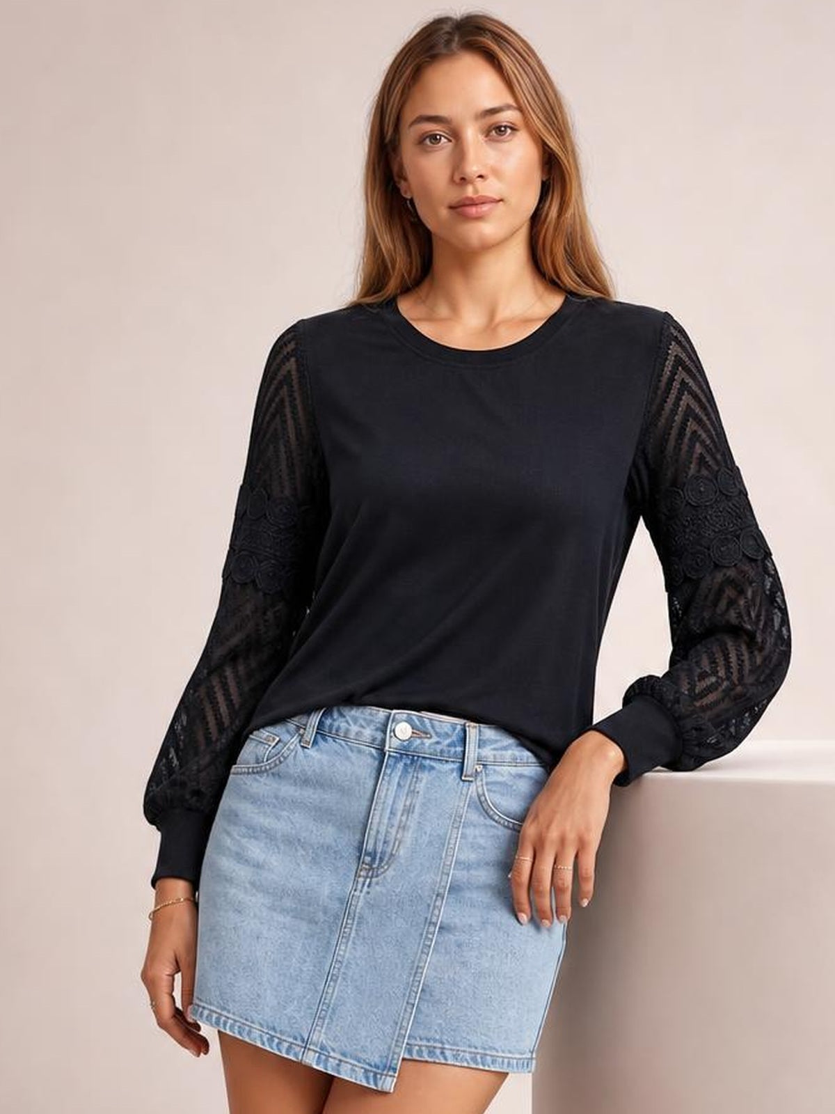 A woman models a solid black round-neck blouse with a relaxed regular silhouette, long sleeves, sheer lace panels, and ribbed cuffs.