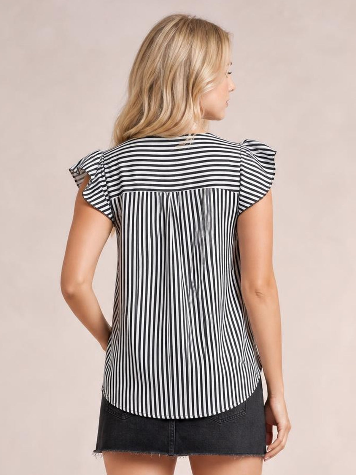 Model shown from behind wearing a black-and-white striped blouse with ruffled cap sleeves, contrasting vertical paneling, a relaxed silhouette, and curved hem.