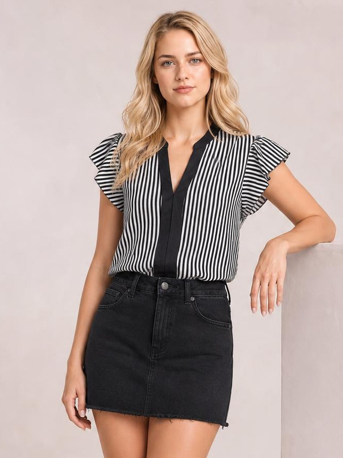 A model poses in a black-and-white striped blouse with a notched V-neck, black trim, ruffled cap sleeves, and a relaxed straight silhouette.