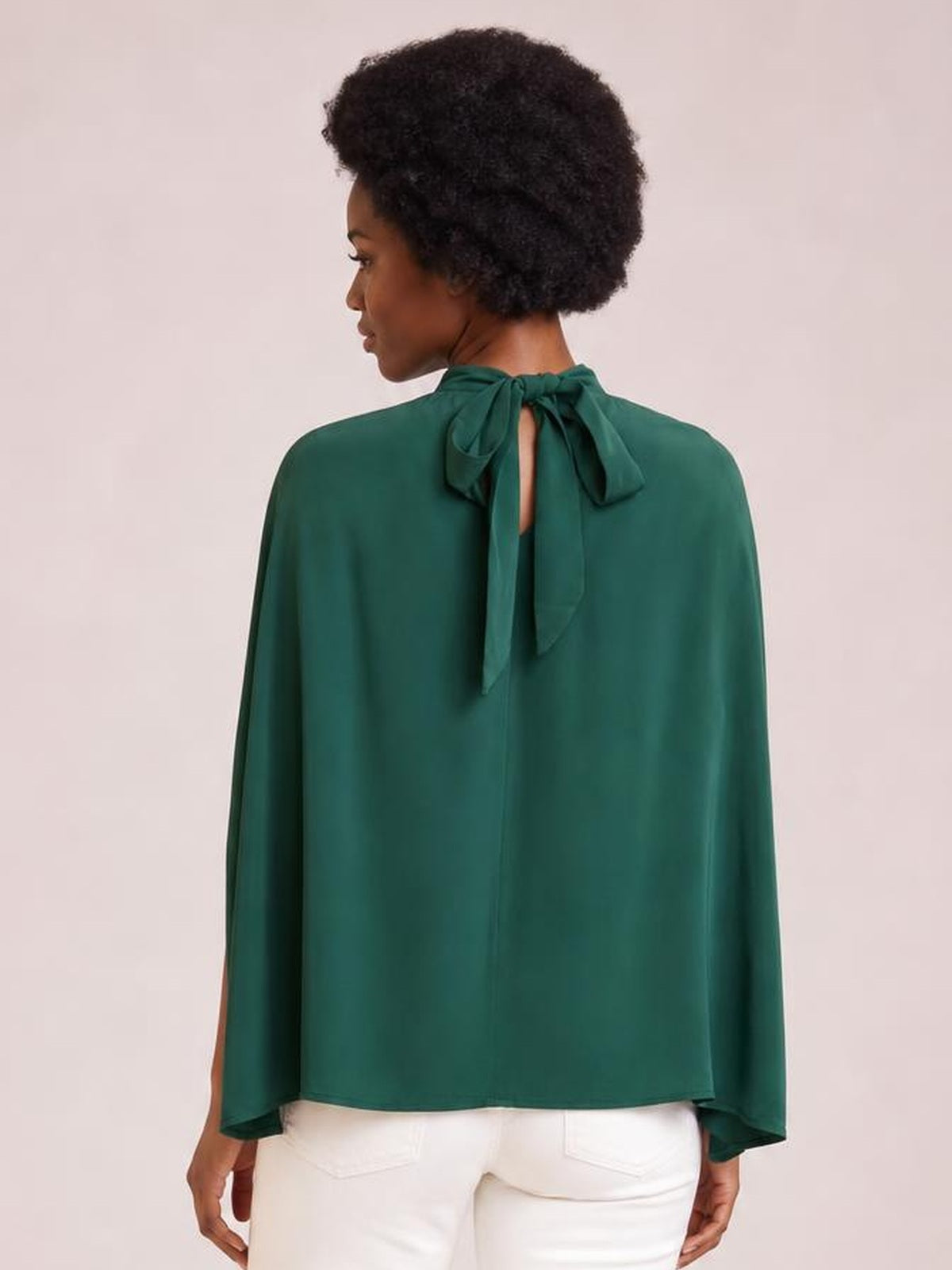 Model shown from the back wearing a solid emerald green mock neck blouse with a tied ruched neckline, split three-quarter sleeves, and a relaxed regular silhouette.
