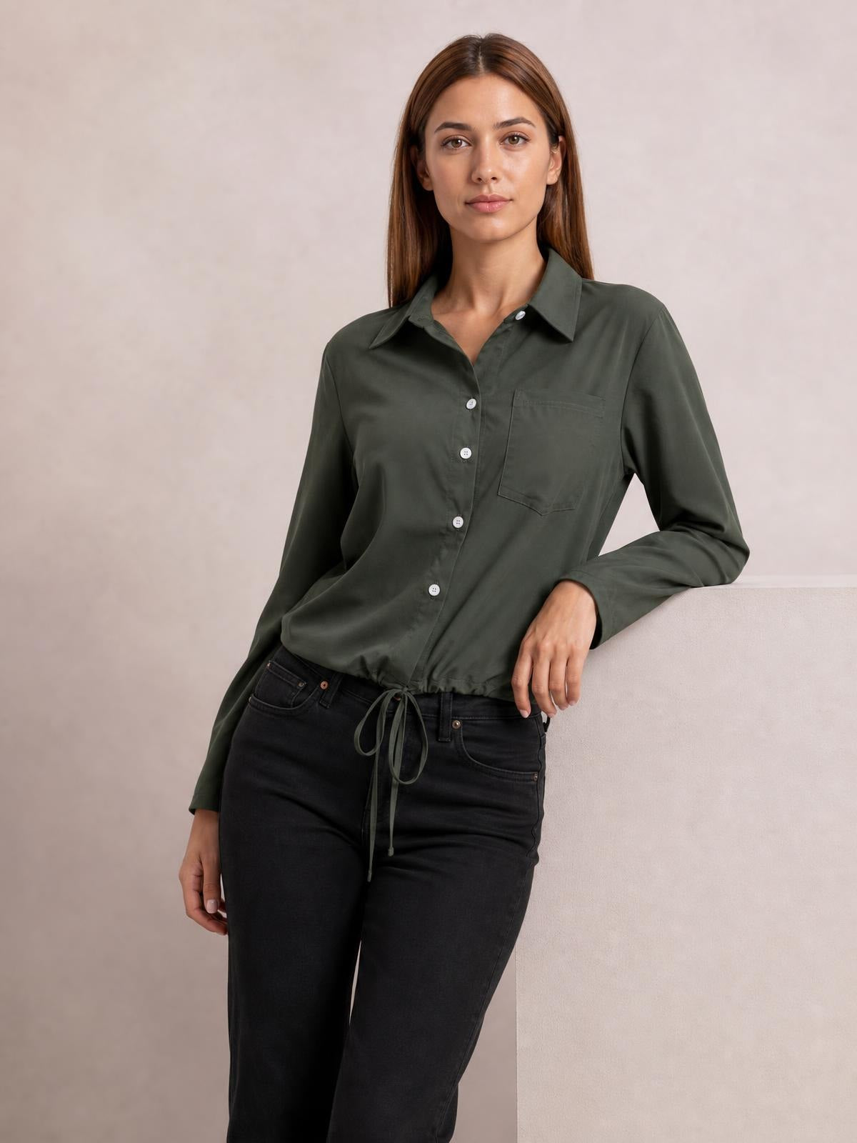 Model wearing an olive green tied hem button-down long-sleeve shirt with a pointed collar, chest pocket, button front, and relaxed silhouette.