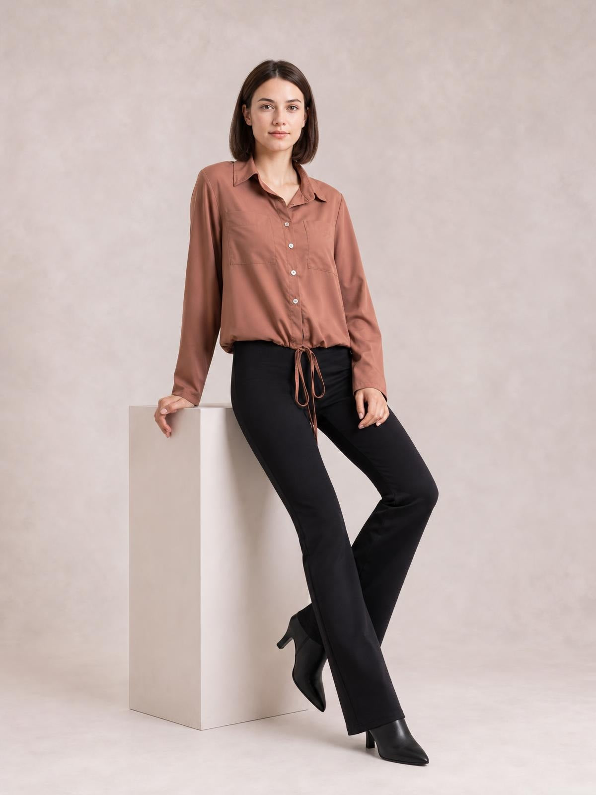 Model wears a brown long sleeve button-down shirt with a collared neckline, front buttons, chest pockets, and a tied hem creating a relaxed silhouette.