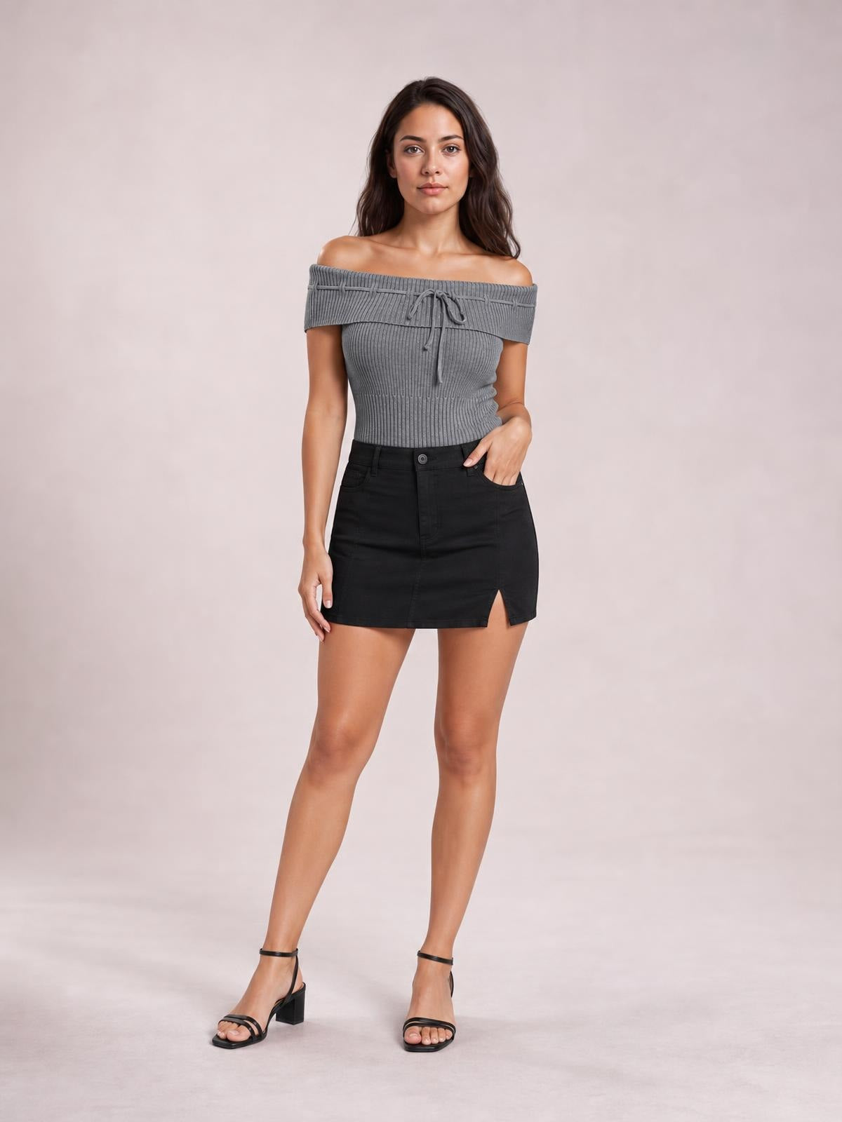 Model poses in a fitted gray ribbed knit top with an off-shoulder neckline, short sleeves, tied front detail, and a cropped silhouette.