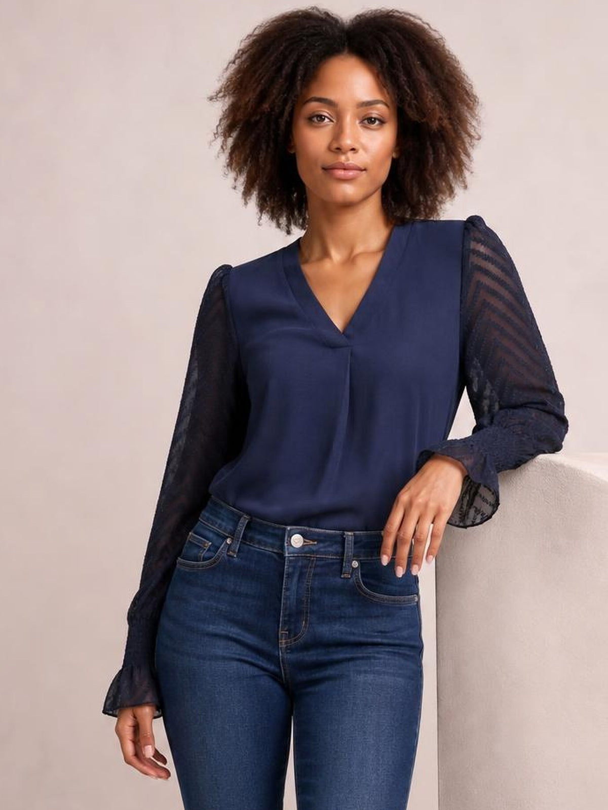 Model poses in a navy V-neck top with long sheer mesh sleeves, gathered shoulders, flared cuffs, and a relaxed straight silhouette.