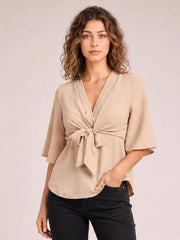 Model wearing a solid beige V-neck blouse with a twisted tie-front detail, relaxed long silhouette, and loose half sleeves.
