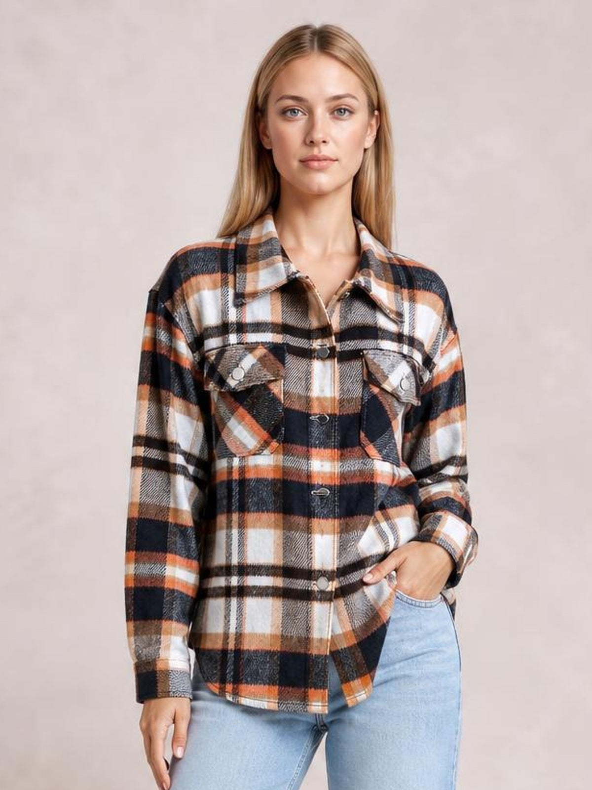 Model wearing a relaxed plaid button-front shirt jacket in black, white, tan, and orange with a collared neckline, long sleeves, dropped shoulders, and breast pockets.