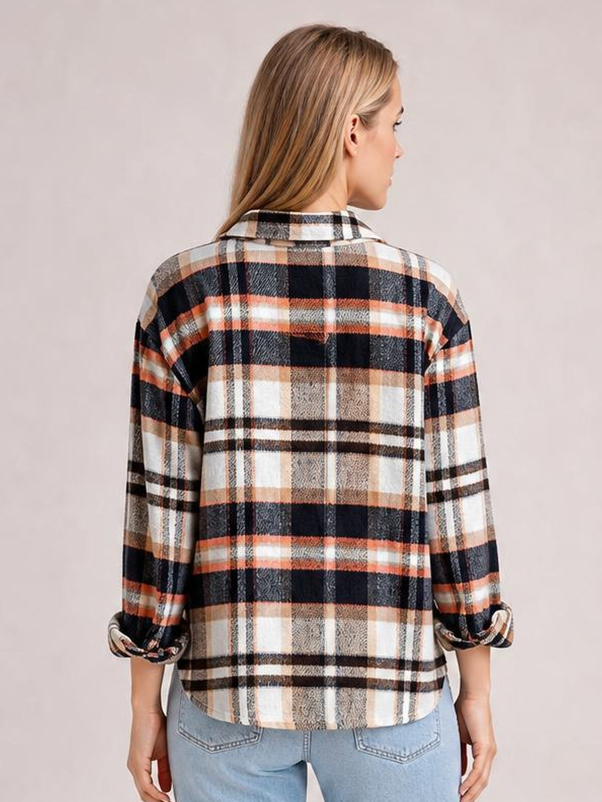 Model shown from the back wearing a relaxed plaid button-front shirt jacket in black, white, tan, and orange with a collared neckline, long dropped sleeves, and rounded hem.